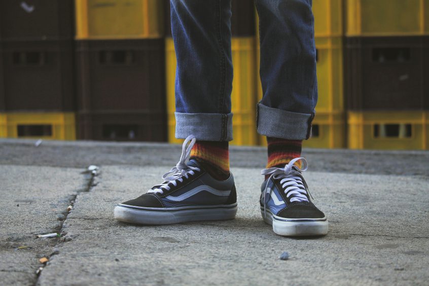 Image of an individual's lower legs showing jeans, socks, and shoes