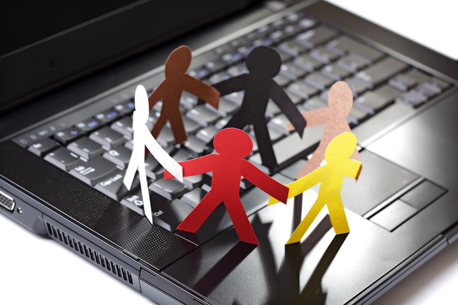 Image of multiple people (paper cutouts) meeting on a computer keyboard