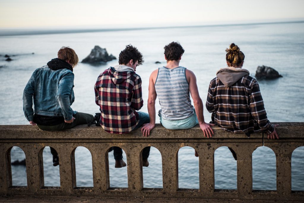 Group of people sitting on barrier overlooking water