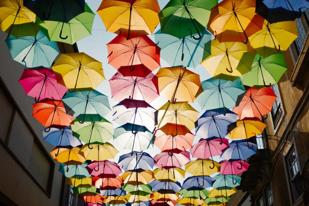 Looking up into a sky full of coloured umbrellas