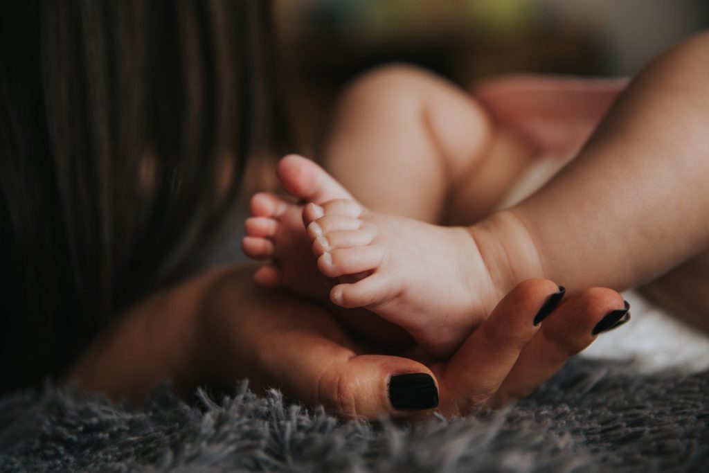 Woman's hand holding an infant's feet