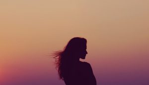 Silhouette of woman under orange sky