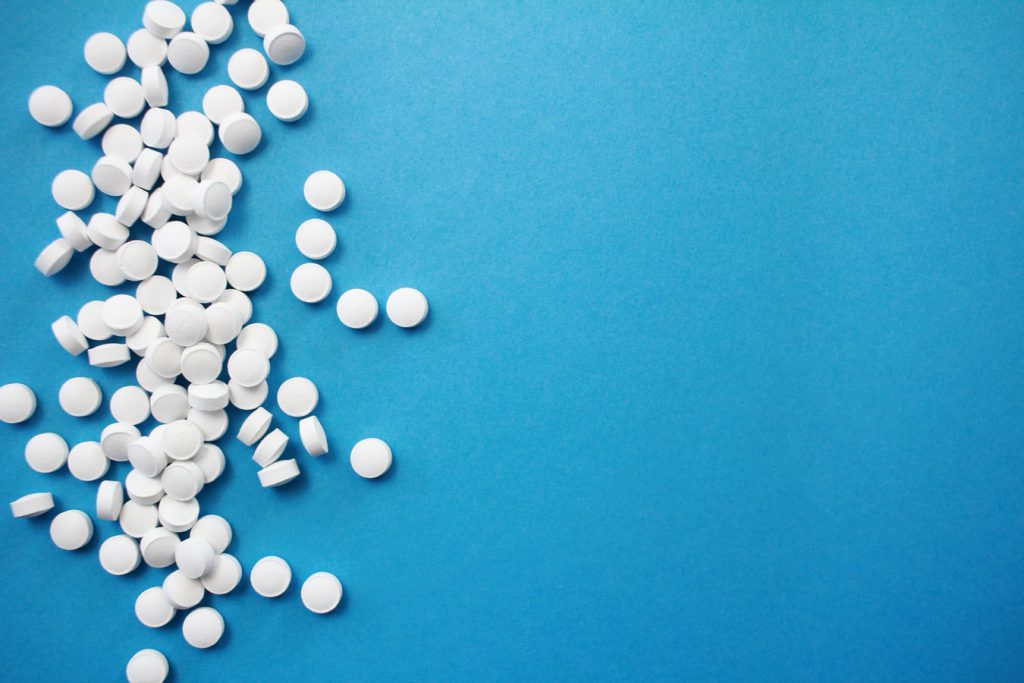 Small white tablets spilled on blue background