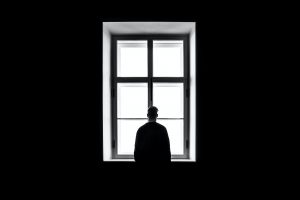 Silhouette of man standing alone face window