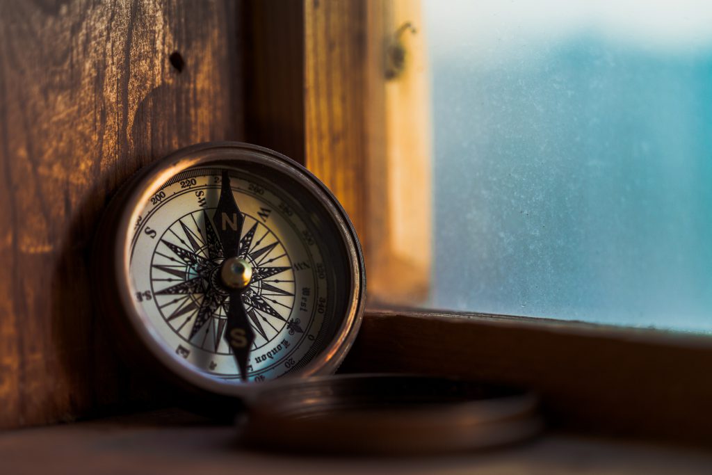A bronze compass sitting in a windowsill