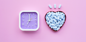 An alarm clock with pills beside it